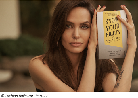 Headshot of Angelina Jolie holding the Know Your Rights and Claim Them book. Image credit: Lachlan Bailey/Art Partner